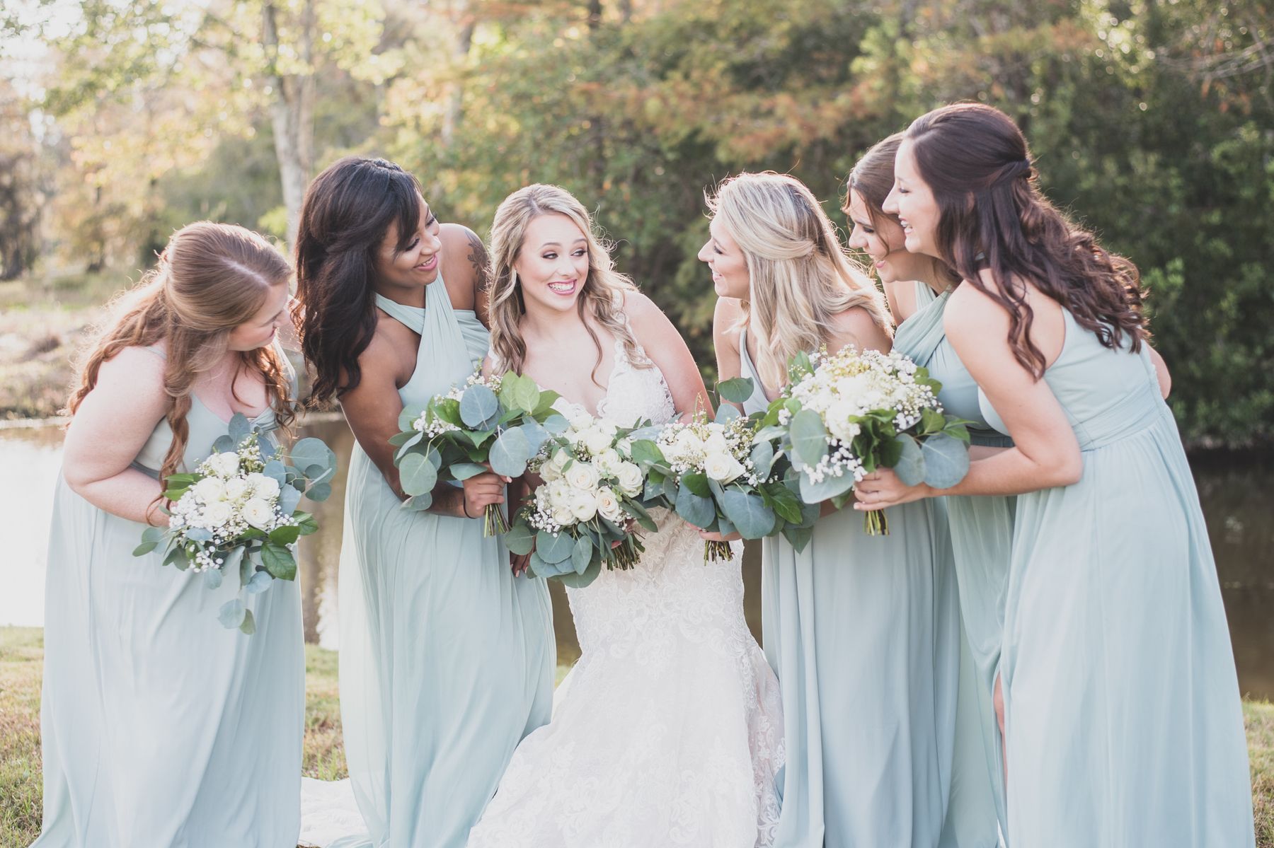 A bride laughing with her bridesmaids by the water at Cypress Landing
