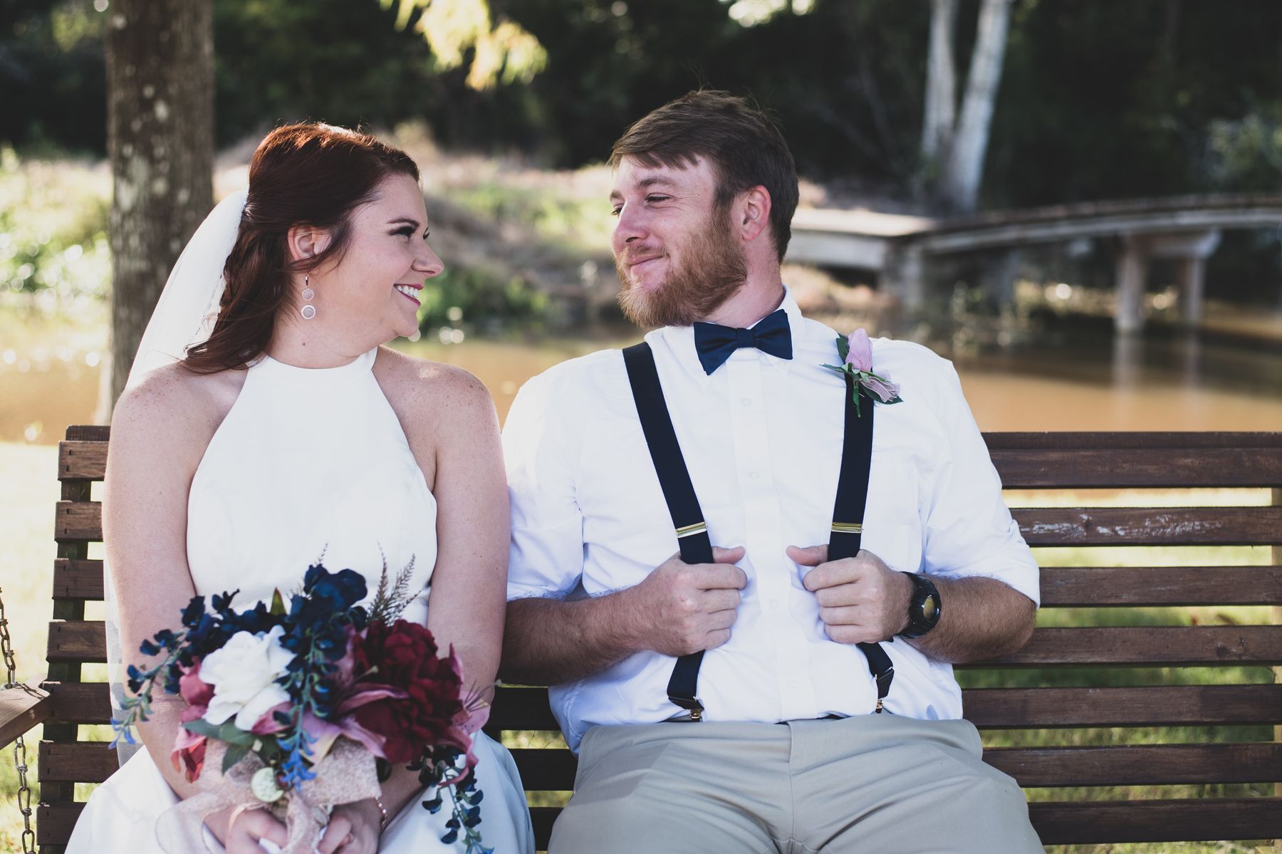 Newlyweds on a porch swing by the water at Cypress Landing